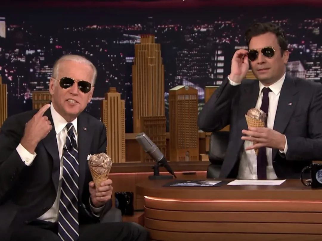 ·拜登（左）在出席晚间脱口秀节目时戴着墨镜，与主持人一起吃冰淇淋。