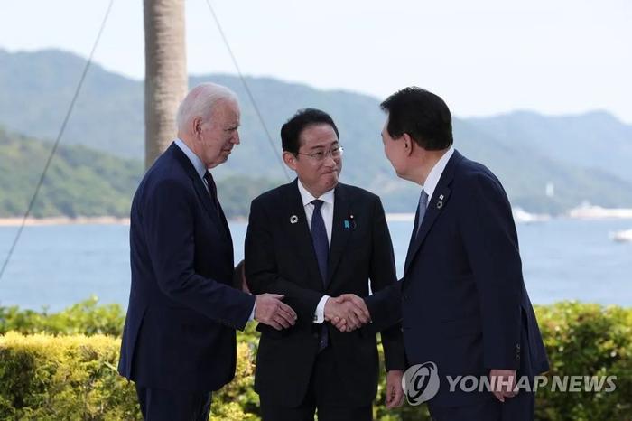 5月21日，韩国总统尹锡悦（右）、美国总统拜登（左一）和日本首相岸田文雄在会谈前握手致意。