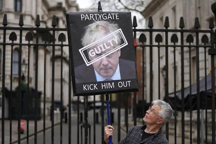 当地时间2022年4月13日，英国伦敦，一名抗议者举着带有“派对门”字样的标语。图/视觉中国