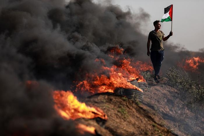 当地时间2023年7月3日，加沙城以东，以色列军事行动期间，一名巴勒斯坦青年在巴以边界围栏前参与抗议活动。
