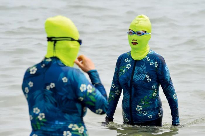 6月24日，山东青岛市，海边浴场内穿戴“脸基尼”防晒服的游客。图/视觉中国