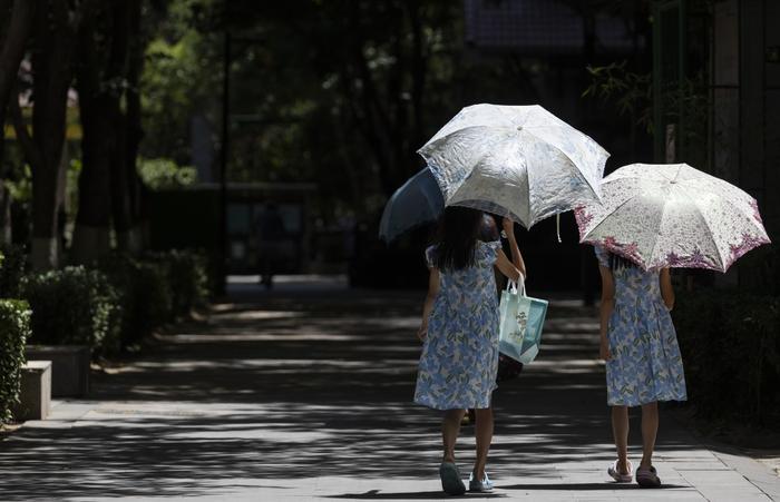 7月6日，北京朝阳，由于气温高、日照强，小朋友打着太阳伞遮阳。  新京报记者 陶冉 摄