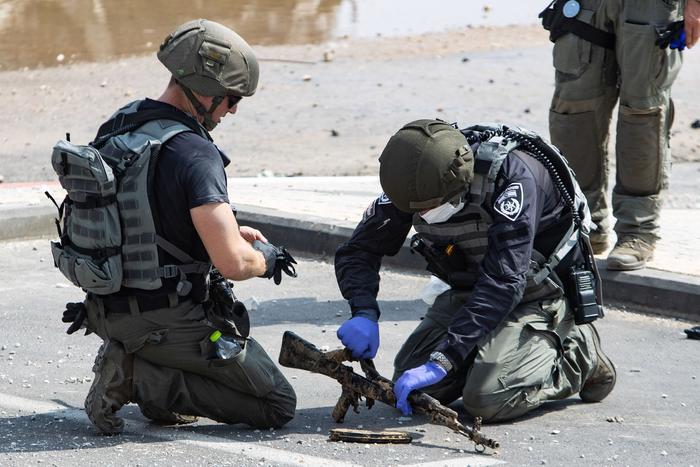 ▲10月8日，在以色列南部城市斯代罗特，以色列警察检查从哈马斯武装人员手中缴获的武器。图/新华社