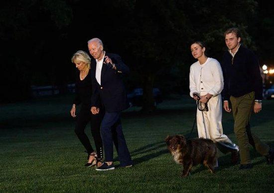 ·拜登夫妇在白宫草坪散步，娜奥米和彼得牵着宠物狗跟在后面。