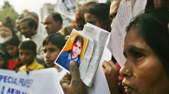 ·失踪儿童的家属举着孩子的照片。
