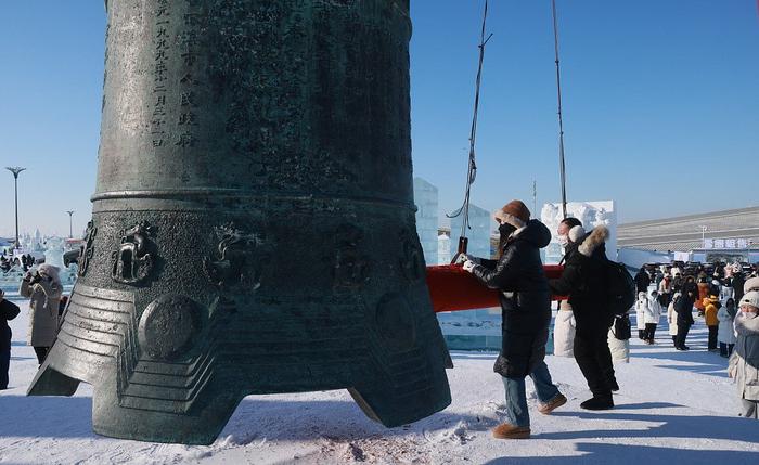 2023年12月31日，元旦假期，哈尔滨冰雪大世界里，游客挂祈福带、撞幸运钟，在新的一年祈福。