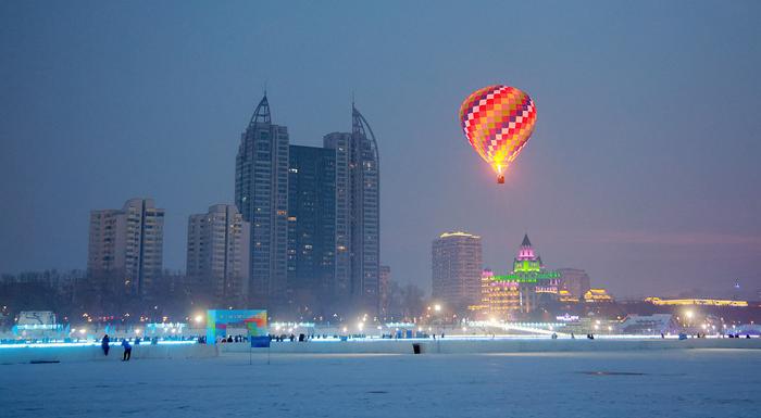 2023年12月29日，哈尔滨，松花江冰雪嘉年华园区，一个颜色鲜艳的热气球成为受游客追捧的热点体验项目。