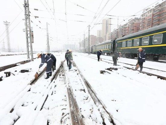 2024年1月22日，湖南娄底站工作人员上铁路线清理道岔关键部位积雪，确保铁路线路畅通。（视觉中国/图）