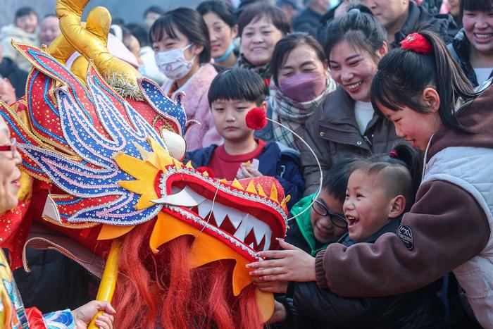 2024年2月10日，在河南商丘古城春节民俗表演巡游活动上，游客与民间舞龙队互动。