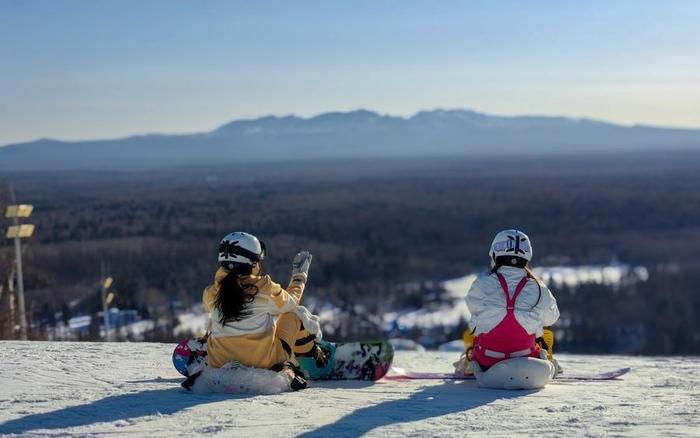 ▲2月2日，雪友在长白山和平滑雪场的雪坡上远眺长白山主峰。图/新华社