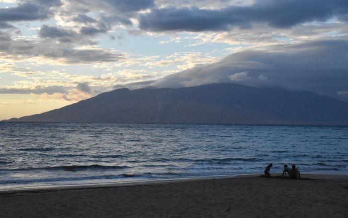 ▲游客坐在美国夏威夷毛伊岛的海滩上。图/新华社