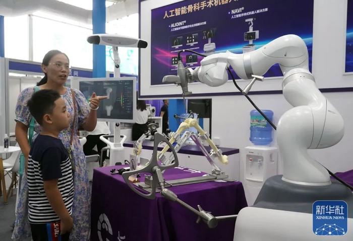 学生在参观了解人工智能骨科手术机器人。图片来源：新华社（记者：任超）